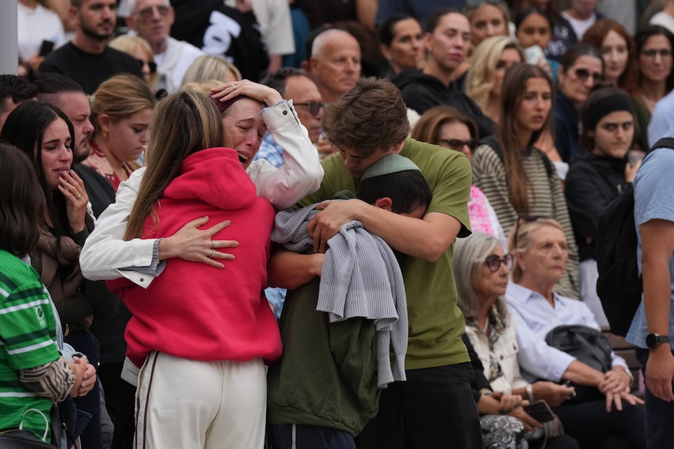 Family members of a victim from Sunday's shooting mourn at a flower memorial made after the...