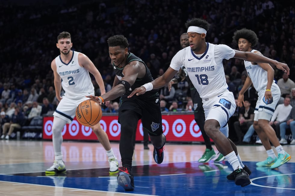 Minnesota Timberwolves guard Anthony Edwards, middle, reaches for the ball against Memphis...